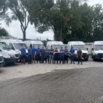 Plumbing and heating team standing beside company service vans