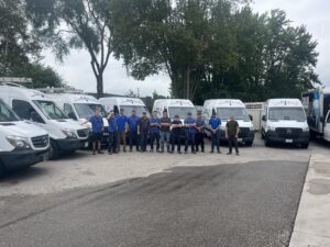 Plumbing and heating team standing beside company service vans